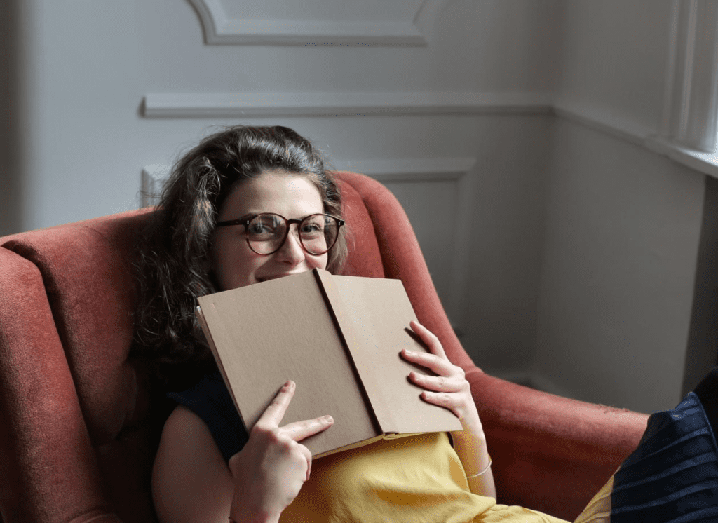 A woman sitting on a sofa chair holding a book